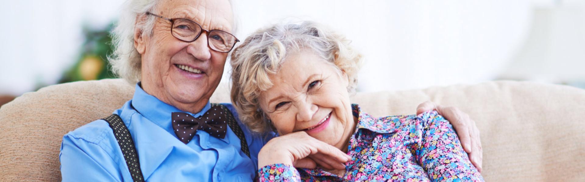 An older couple smiling together on a sofa