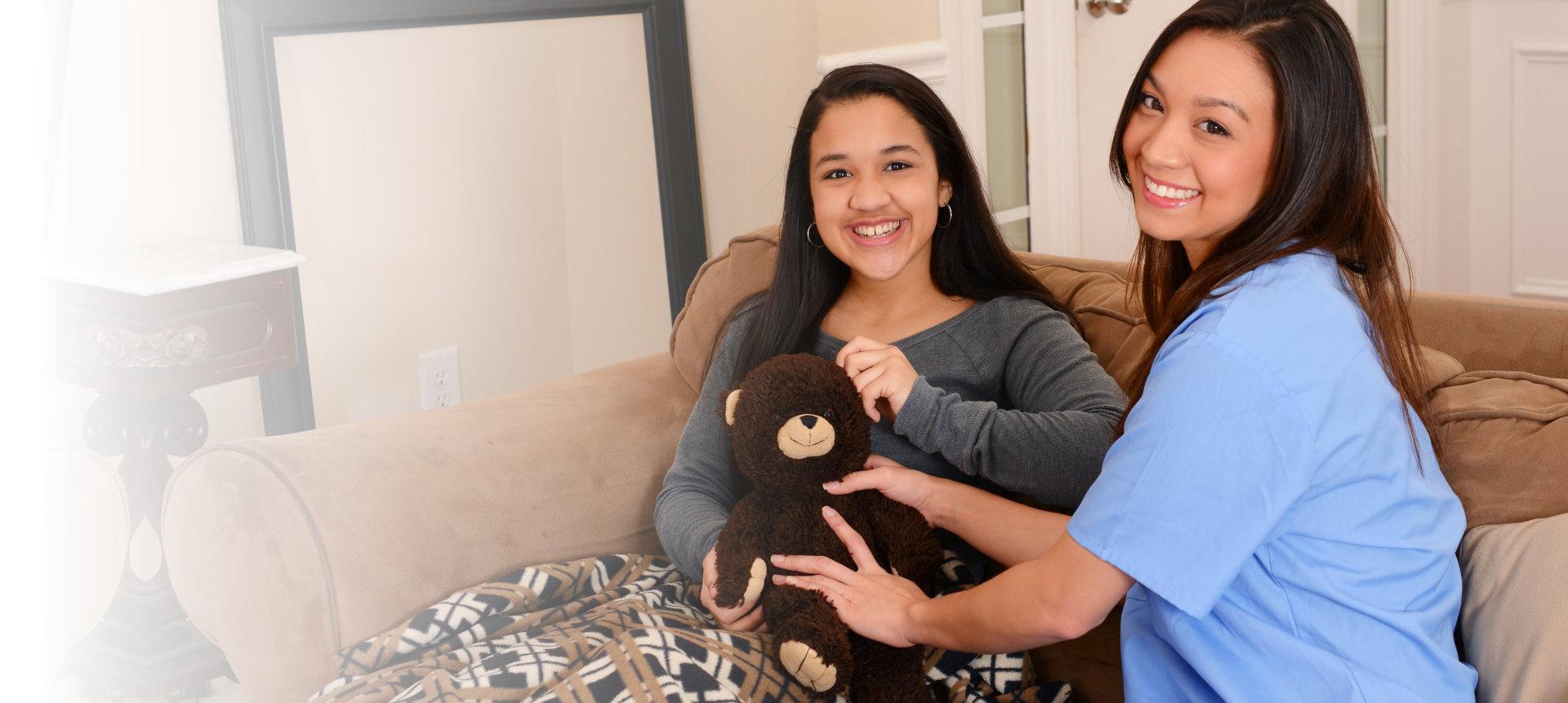 A caregiver and a young woman sharing a moment with a teddy bear